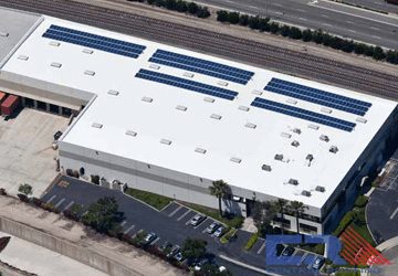 Arial view of white industrial building with white roof with skylights and Air Conditioning units with solar panels