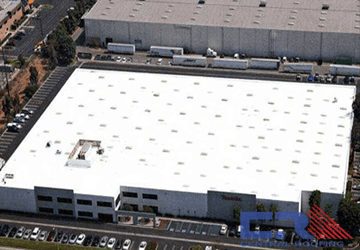 Arial view of white industrial building with white roof with skylights and Air Conditioning units