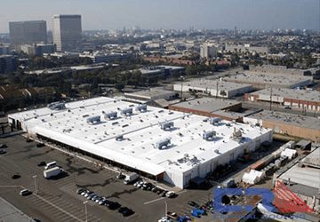 Arial view of white industrial building with white roof with skylights and Air Conditioning units