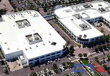 Arial view of two white industrial building with white roof with skylights and Air Conditioning units