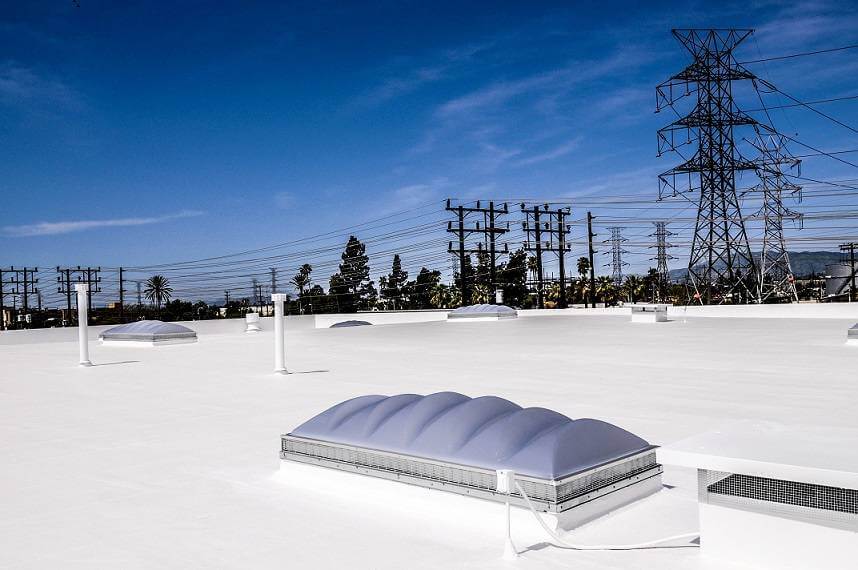 Skylights on white industrial roof with many power poles in the background